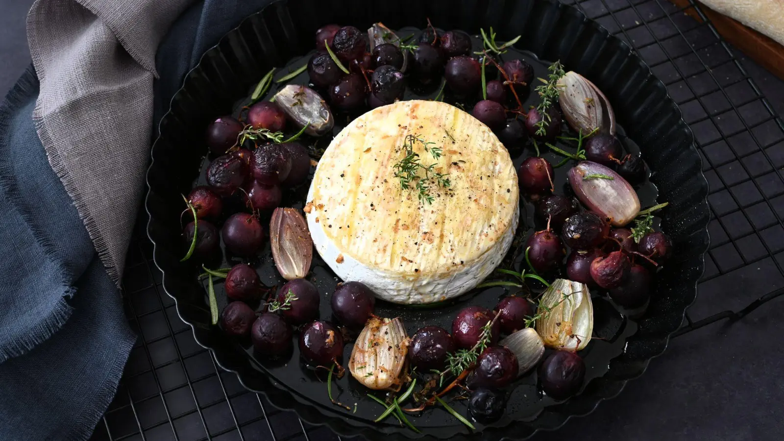 Der Camembert kommt in die Mitte, Schalotten und Tafeltrauben drumherum. Getoppt mit einem würzigen Dressing kommt das Blech in den Ofen. (Foto: Julia Uehren/loeffelgenuss.de/dpa-tmn)