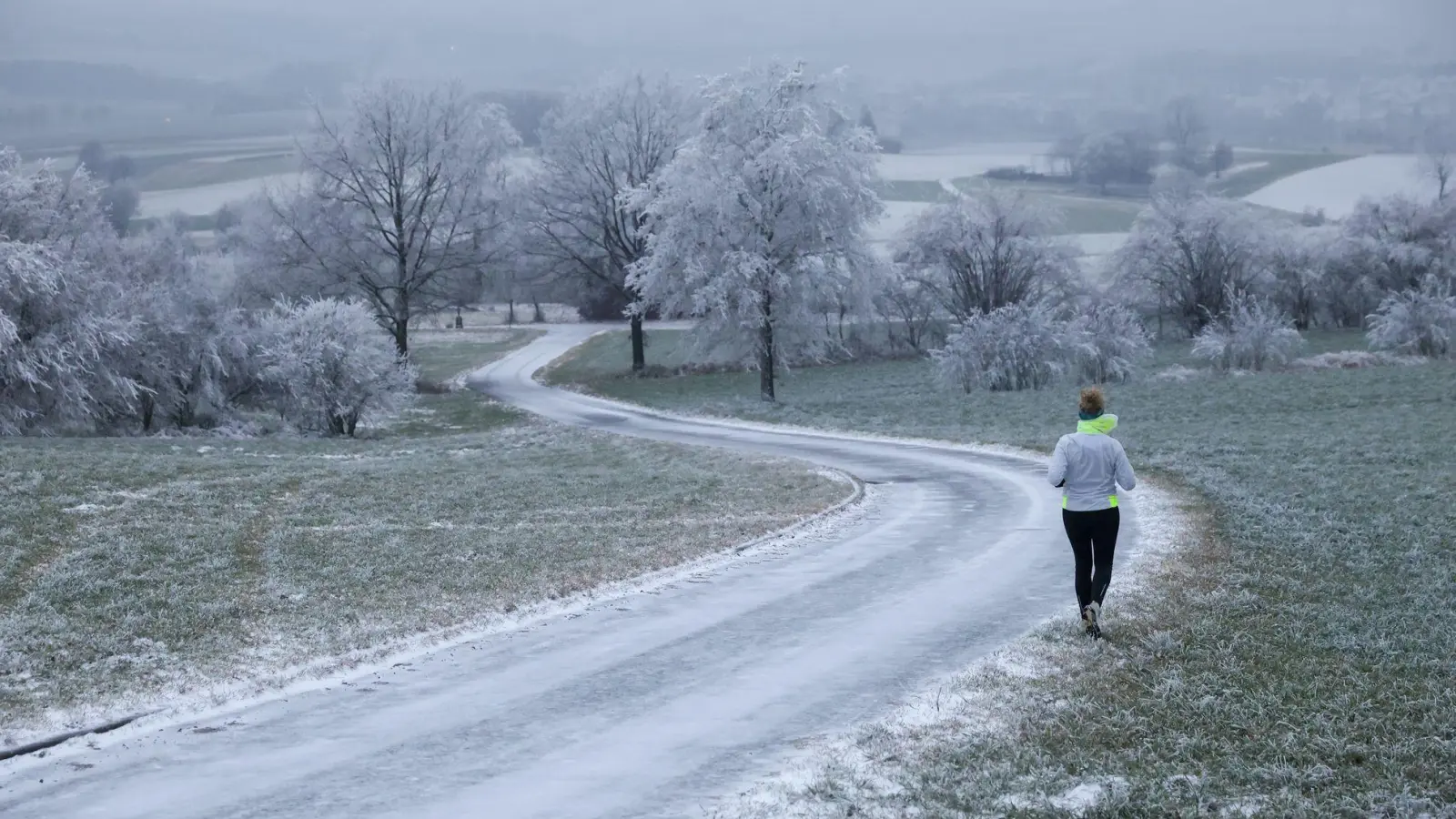 Joggerin trotzt Schnee und Raureif an Heiligabend in Uttenweiler (Foto: Thomas Warnack/dpa)