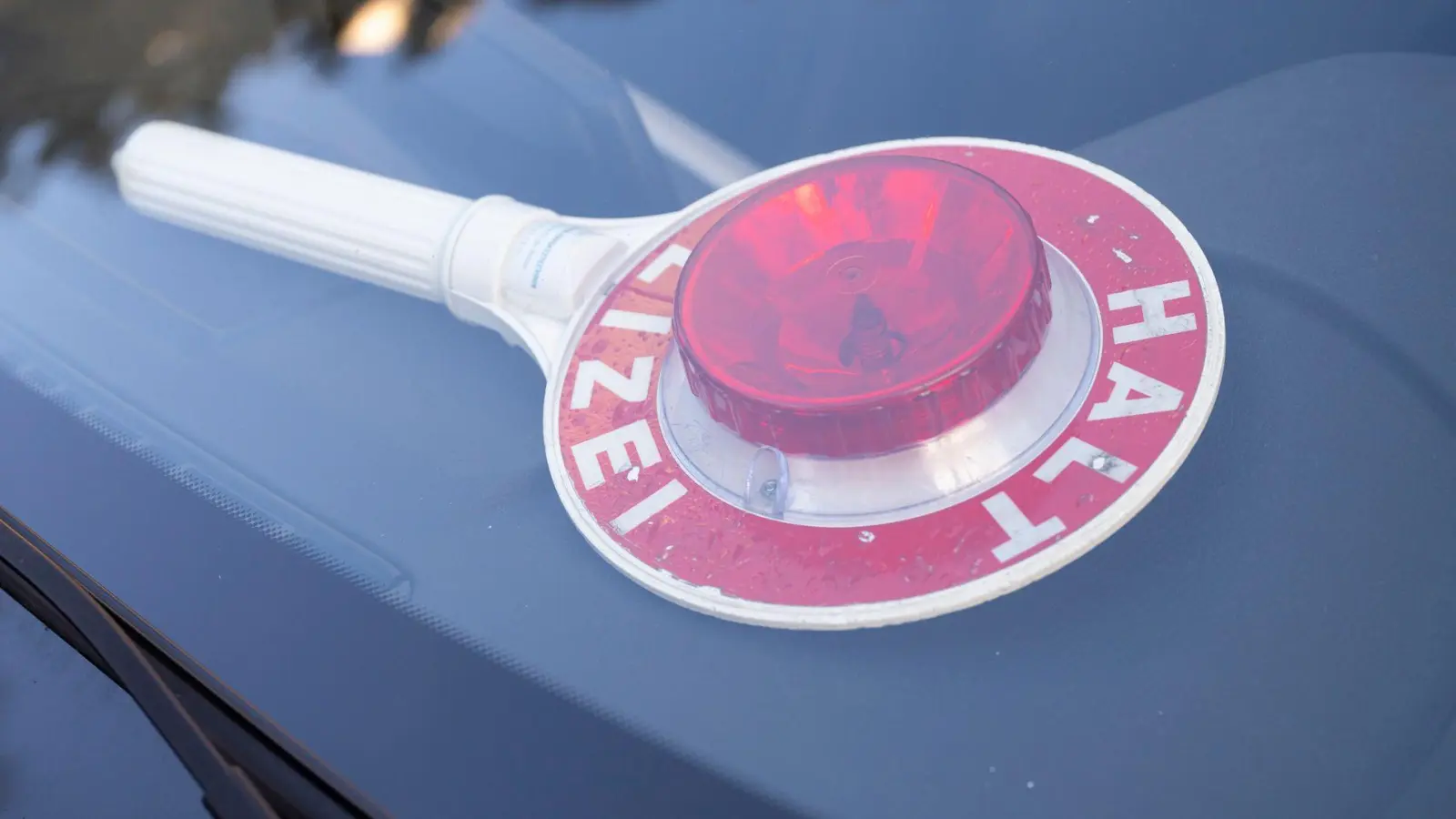 Eine Polizeikelle liegt hinter der Windschutzscheibe eines Zivilfahrzeugs. (zu dpa: «Einige Kilometer zu weit gefahren - Fahrschülerin angezeigt») (Foto: Peter Kneffel)