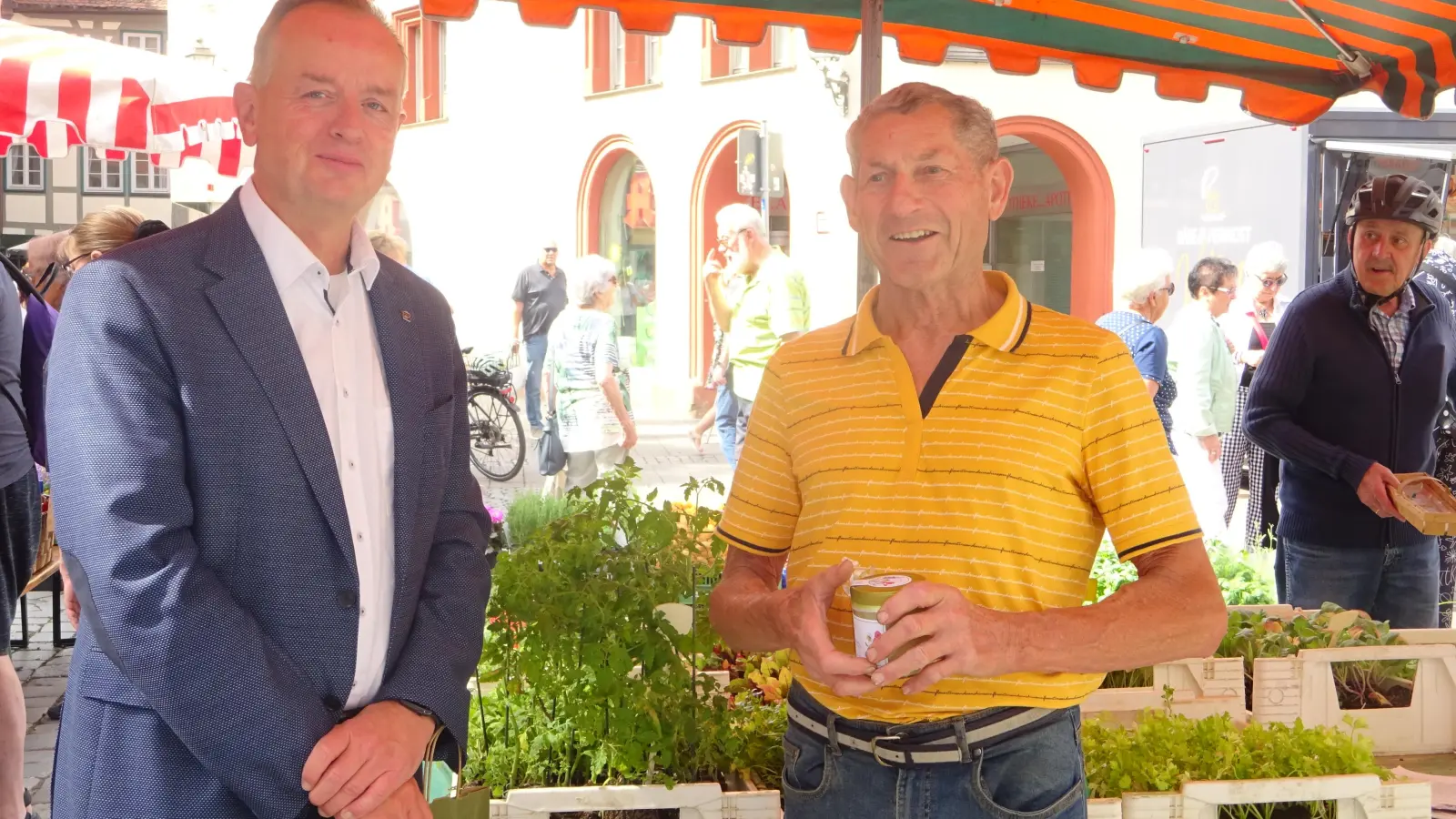 Hans Böhm (re.) hört nach 63 Jahren als Händler auf dem Wochenmarkt in Ansbach auf. Oberbürgermeister Thomas Deffner verabschiedete ihn und bedankte sich mit einem Glas Stadthonig für das Engagement. (Foto: Florian Pöhlmann)