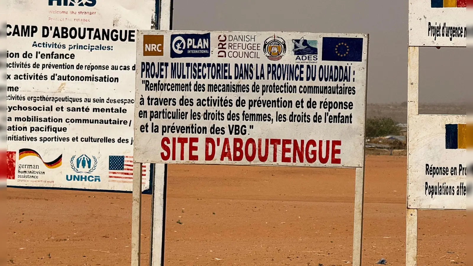 Auf dem Gelände eines Lagers für Flüchtlinge aus dem Sudan im Osten des Tschads stehen die Logos von Hilfsorganisationen, die dort im Einsatz sind. (Archivbild) (Foto: Eva Krafczyk/dpa)