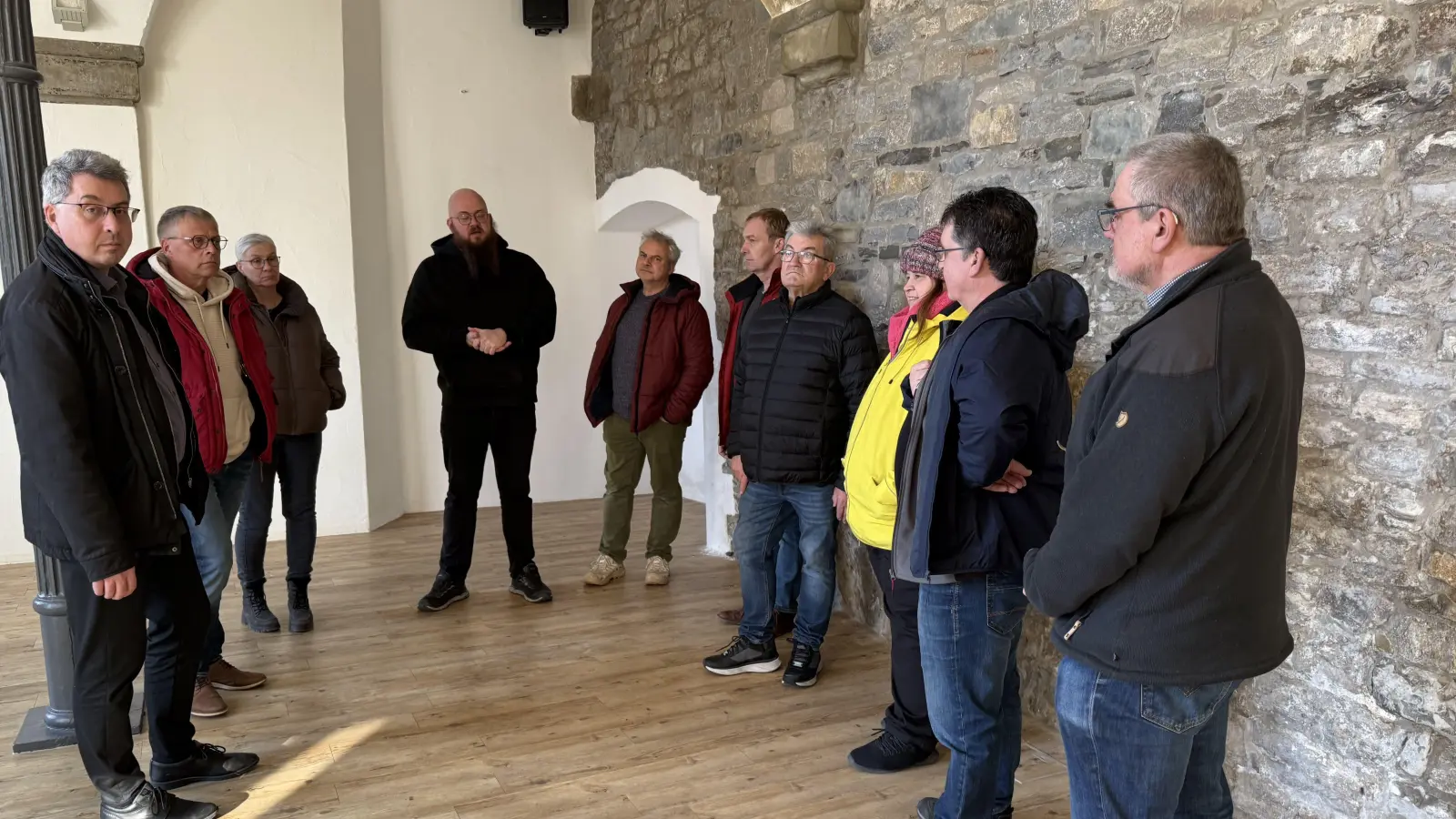 Der größte Raum, der an die Stadtmauer grenzt - das könnte das Herzstück des neuen Jugendtreffs im Wolff’schen Bau werden: Bürgermeister Wolfgang Lampe, Bernhard Schurz, Andra Weber (Stadtbauamt), Konrad Schmitt, Wolfgang Fink, Achim Endreß, Ewald Geißendörfer, Susanne Holzmann, Andreas Schober sowie Uwe Strebel (von links) während des Rundgangs durch das Gebäude in der Würzburger Straße. (Foto: Sylvia Fehlinger)