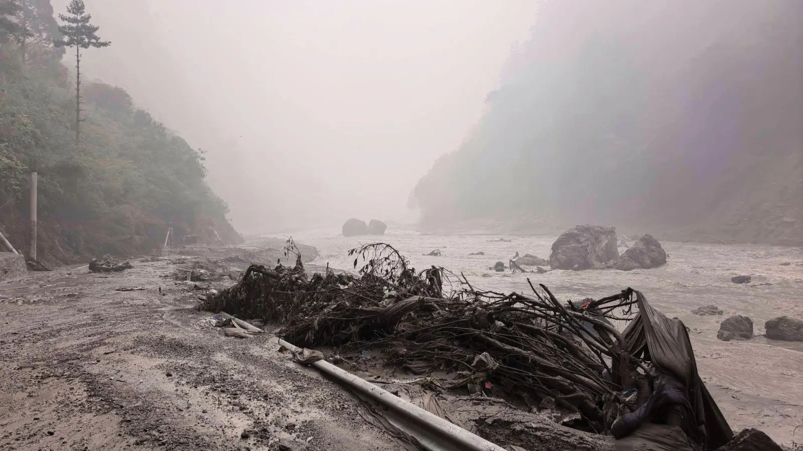 Auf diesem von der Nachrichtenagentur Xinhua veröffentlichten Foto ist ein schlammiges Flussufer mit Trümmern in der Nähe des Hafens von Gyirong in der Autonomen Region Tibet im Südwesten Chinas zu sehen. (Foto: Anonymous/Xinhua/AP/dpa)