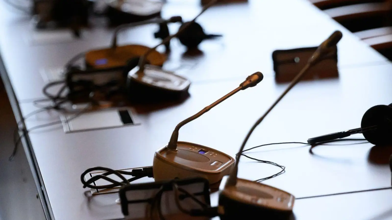 Mikrofone und Kopfhörer auf einem Tisch in einem Gerichtssaal. (Foto: Jonas Walzberg/dpa/Symbolbild)