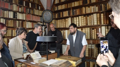 Martin Frenkler, Pfarrer im Ruhestand (Bildmitte) betätigte sich im Anschluss an seine Amtseinführung in der Bibliothek bereits als Erklärer für den Neustädter Bücherschatz.  (Foto: Patrick Lauer)