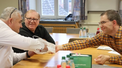 Bürgermeister Claus Seifert (links) zieht in seiner Funktion als Wahlausschussvorsitzender eines der Lose, die Georg Münich (rechts) vorbereitet und in eine Papiertüte geworfen hatte. Hans Müller, CSU-Vertreter im Wahlausschuss, beäugt den Vorgang. (Foto: Andreas Reum)