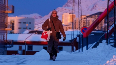 Eine Frau geht bei Sonnenuntergang auf einer Straße in Nuuk. (Foto: Evgeniy Maloletka/AP/dpa)