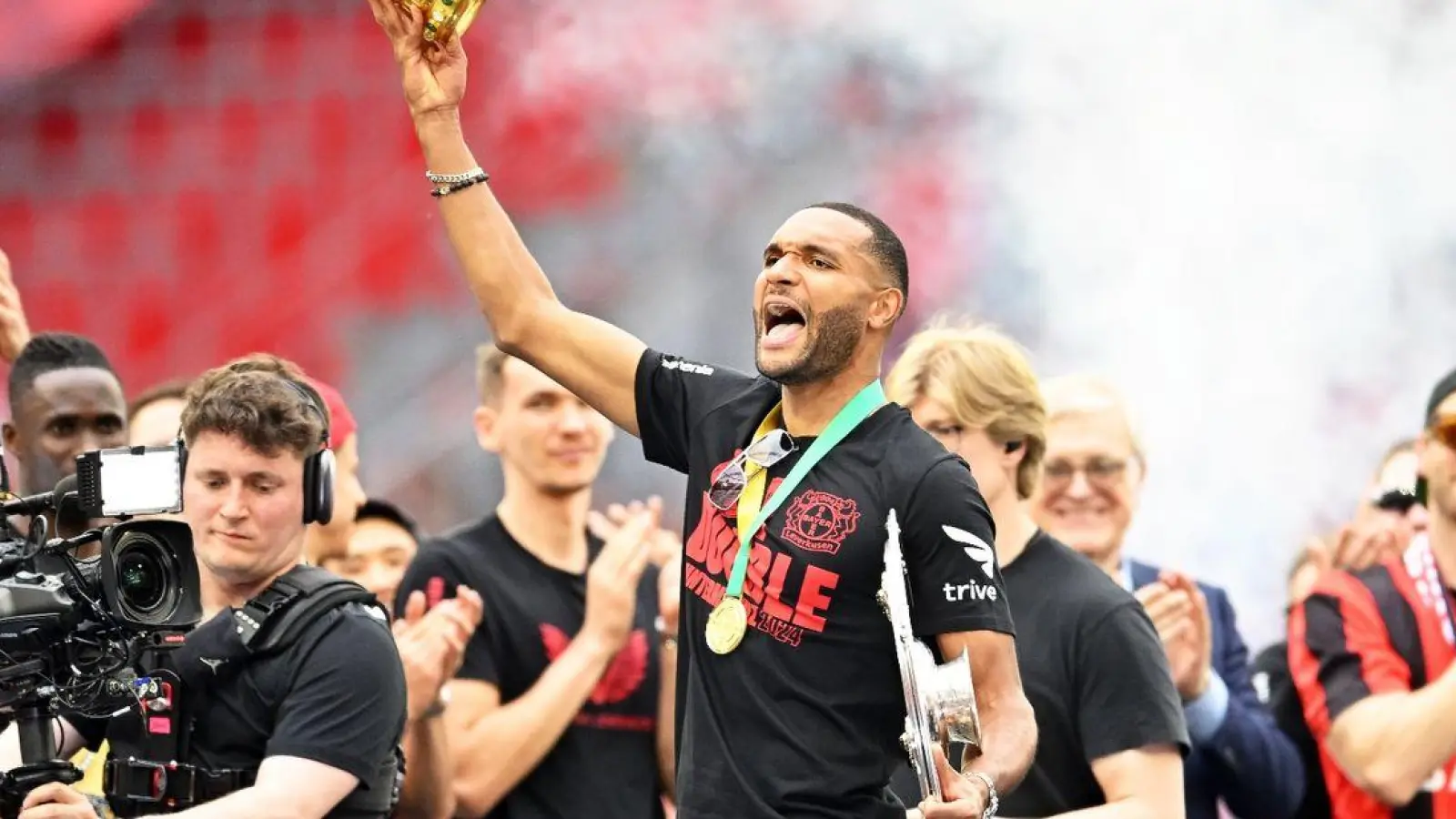 Leverkusens Jonathan Tah (M) präsentiert bei der Meisterfeier in der BayArena die Meisterschale und den Pokal. (Foto: Marius Becker/dpa)