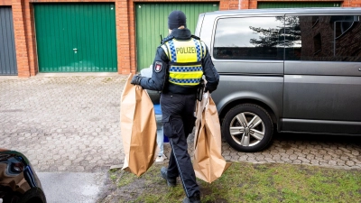 Eine Polizistin trägt Beweismittel aus einem Mehrfamilienhaus. Eine Hundertjährige soll dort von ihrem Enkel getötet worden sein. (Foto: Daniel Bockwoldt/dpa)