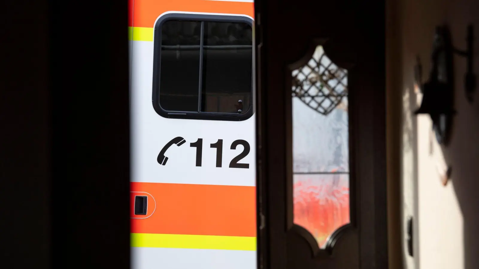 Ein Rettungswagen parkt vor der geöffneten Tür eines Wohnhauses. (Foto: Boris Roessler/dpa/Symbolbild)