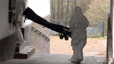Beamte der Spurensicherung bringen eine Trage in ein Wohnhaus.  (Foto: Thorsten Kremers/dpa)
