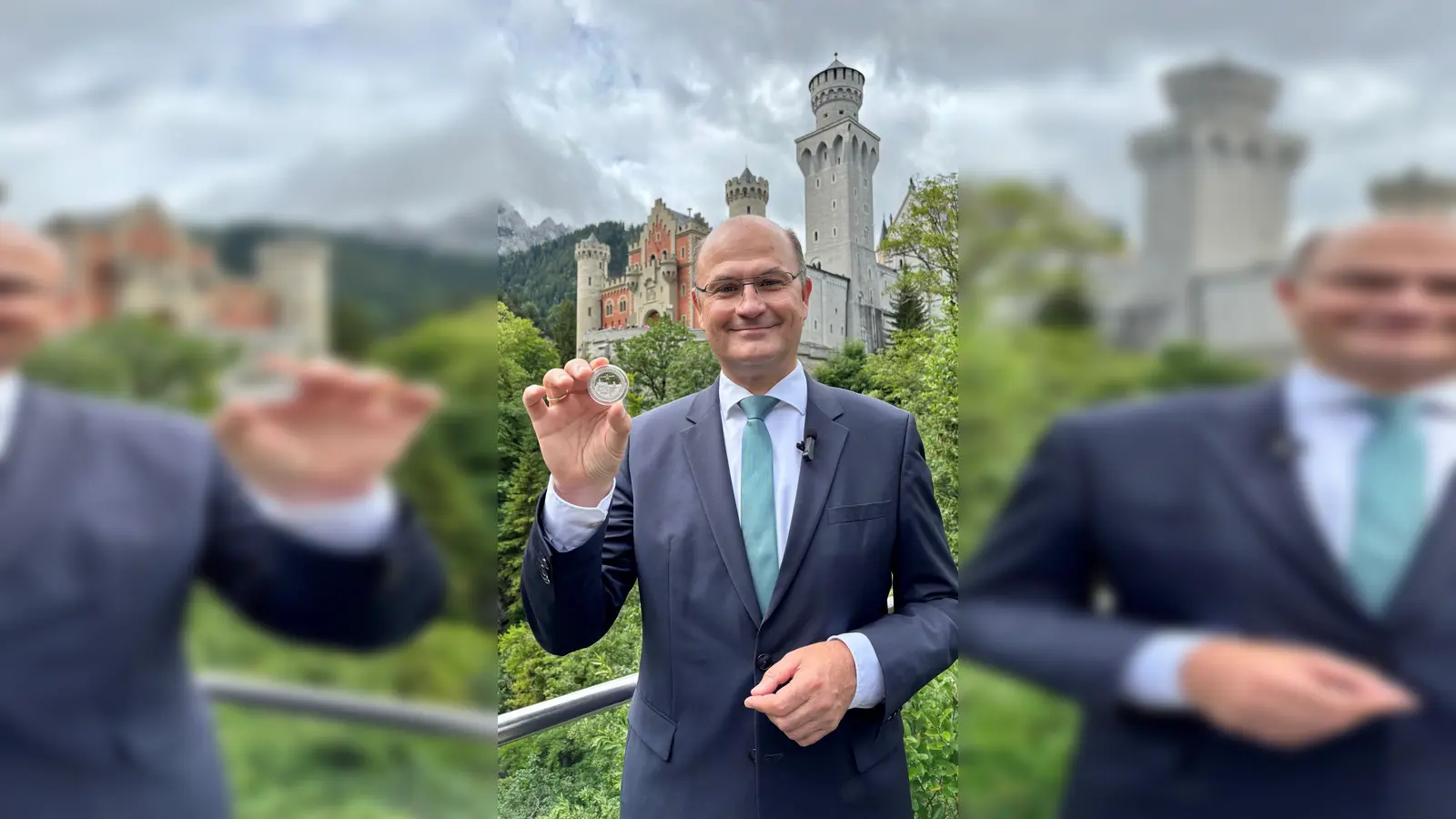 Finanzminister Albert Füracker (CSU) mit dem „Bayern Thaler“ in der Hand vor Schloss Neuschwanstein. (Foto: -/Bayerisches Finanzministerium/dpa)
