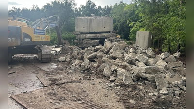Große Betonteile lagern derzeit auf der Petersauracher Seite der ehemaligen Brücke. Ein Spezialunternehmen ist gerade dabei, die tonnenschweren Stücke zu zerkleinern. (Foto: Florian Pöhlmann)