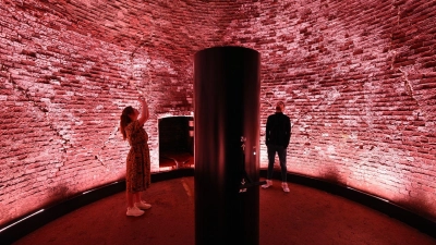 Höllenmaschine mit Lichtkunst: Der 98 Meter hohe Schornstein der Kokerei Zollverein leuchtet rot als Teil des erweiterten Denkmalpfads. (Foto: Federico Gambarini/dpa/dpa-tmn)