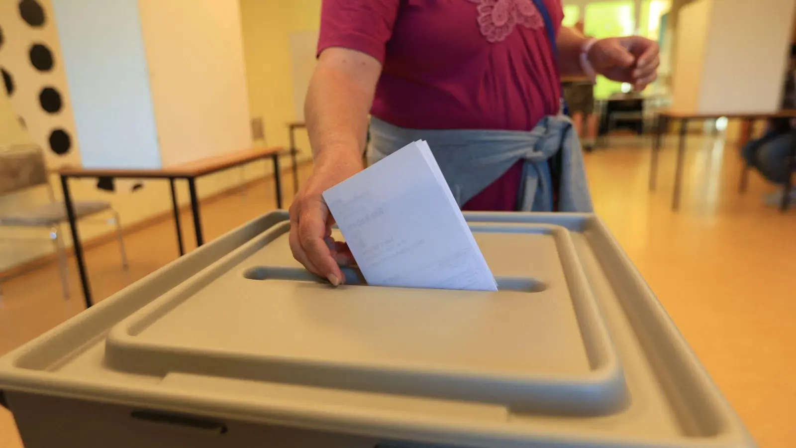 Eine Wählerin wirft in einem Wahllokal in Wernigerode ihren Stimmzettel in eine Wahlurne. (Foto: Matthias Bein/dpa)