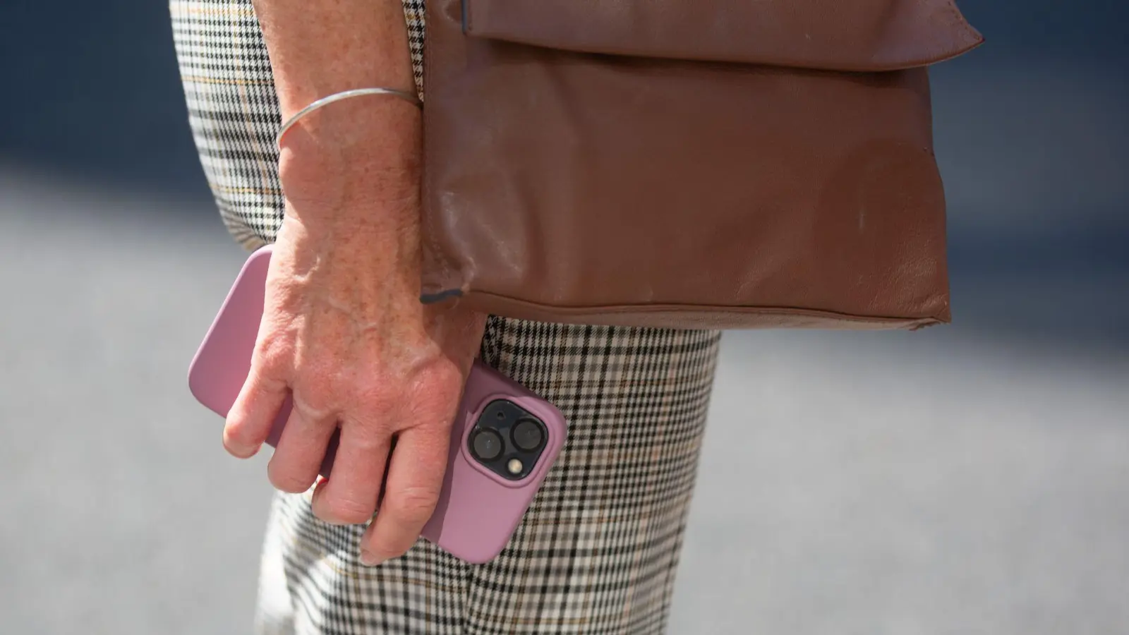 Eine ältere Frau hält ein Smartphone mit pinkfarbener Hülle in der Hand. Sie trägt eine karierte Hose und eine braune Umhängetasche. (zu dpa: «Handydiebstahl in London: Polizei gelingt Schlag gegen Bande») (Foto: Fernando Gutierrez-Juarez)