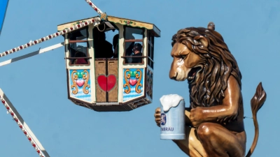 Wiesn-Besucher fahren in einem Riesenrad auf dem 190. Münchner Oktoberfest an der Kulisse einen überdimensionalen Löwen mit Bierkrugs vorbei. (Foto: Peter Kneffel/dpa)