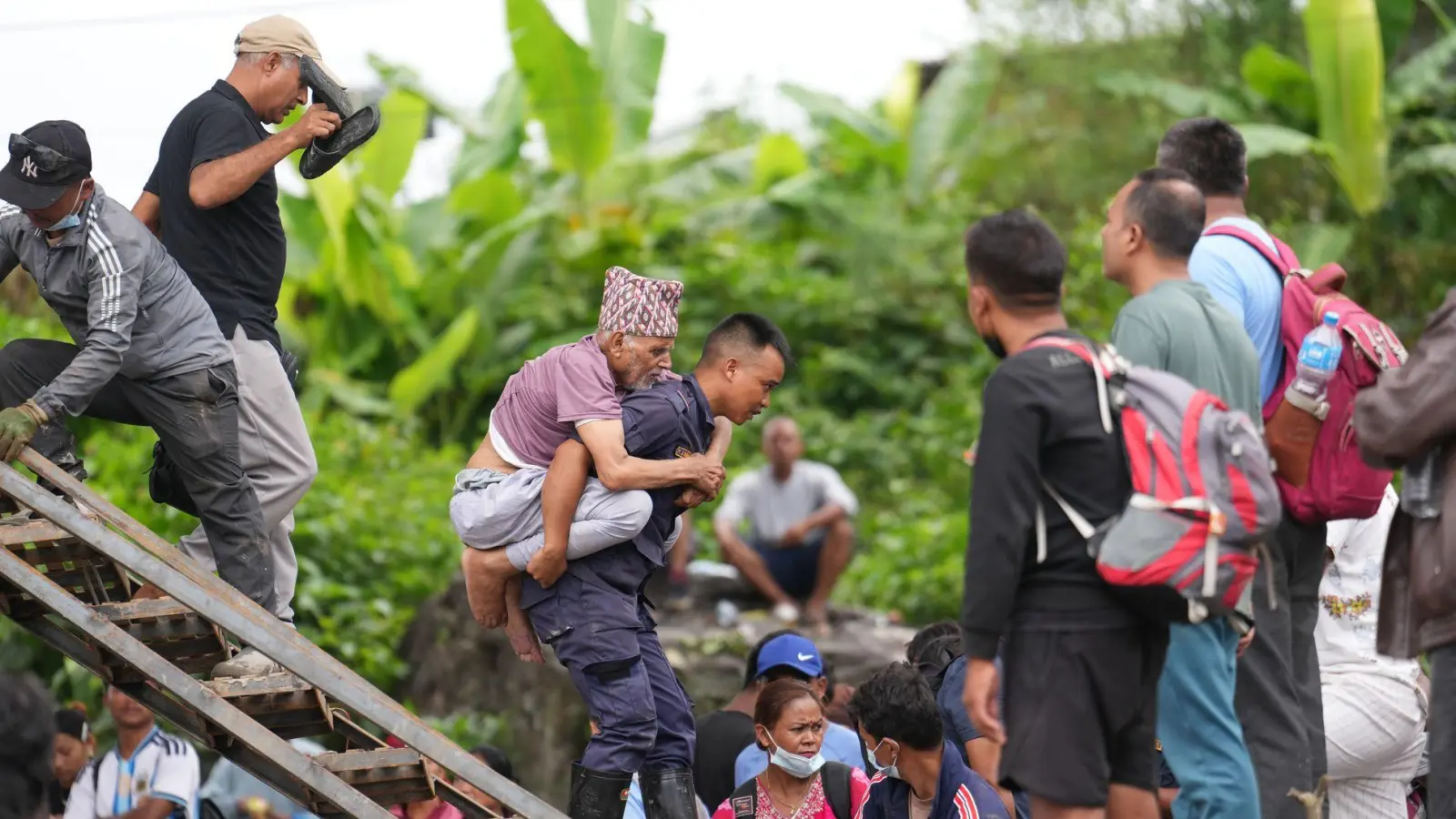 Ein Mann wird im Katastrophengebiet in Nepal von einem Polizisten auf dem Rücken getragen. (Foto: Rajesh Kumar Singh/AP/dpa)