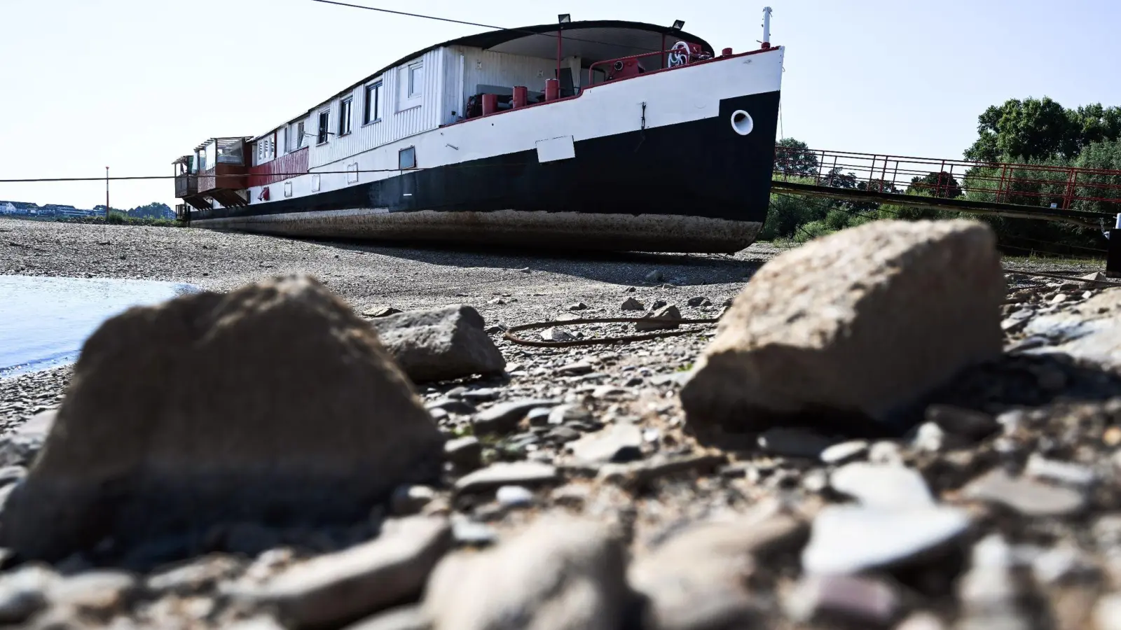 Trockengefallen liegt ein Schiff zwischen den Buhnen am Rhein bei Düsseldorf. (Foto: Federico Gambarini/dpa)