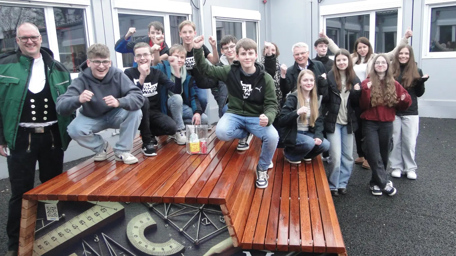 Stolz präsentieren die Schülerinnen und Schüler der 8a Werken Talent der Realschule Heilsbronn ihre Sitzmöbel – hier die Mathematik-Sitzbank. Zimmermeister Marco Roß (links) und Firmenchefin Anja Lederer (3. von rechts) haben ihnen beim Bau geholfen. Mitten im Pulk der Schüler: Lehrerin Anke Schwarz und der stellvertretende Landrat Hans Henninger. (Foto: Winfried Vennemann)