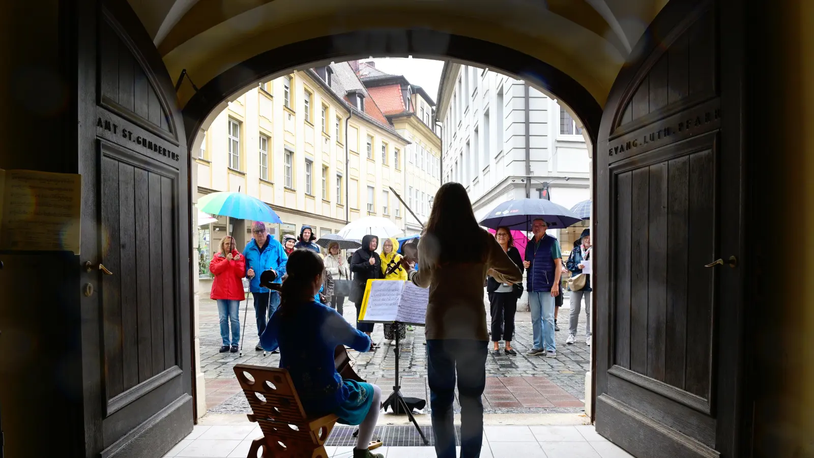 Gut geschützt war der Streicher-Nachwuchs im Torbogen des Pfarramtes von St. Gumbertus. Das Publikum lauschte unter einem Dach aus Regenschirmen. (Foto: Jim Albright)