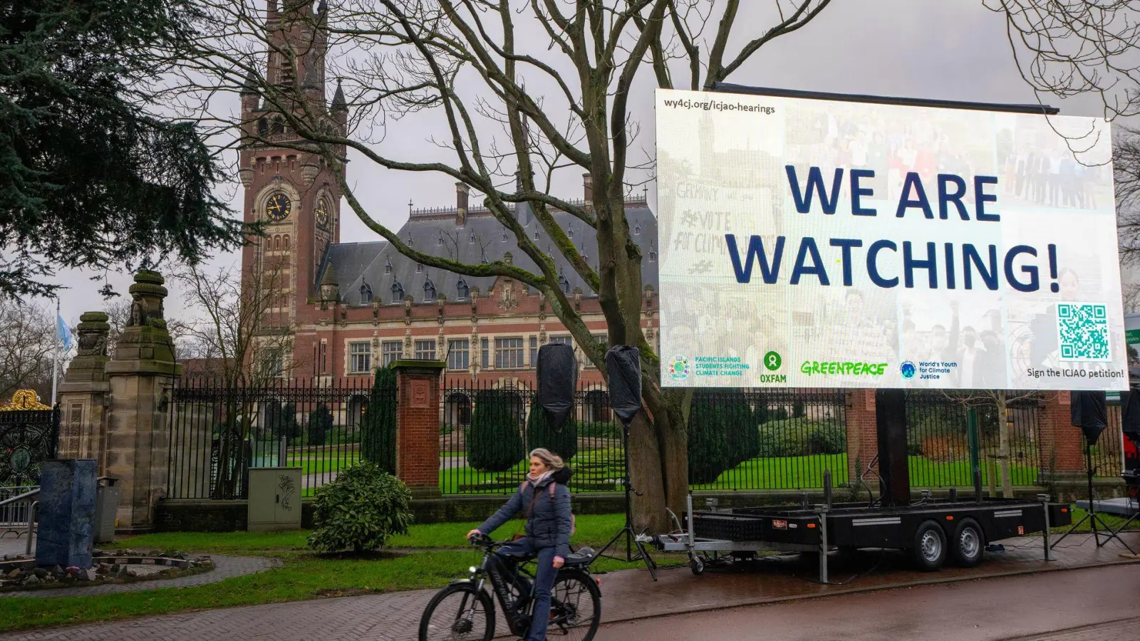 „We are Watching!“ ist auf einem Plakat vor dem Internationalen Gerichtshof zu lesen: Das höchste UN-Gericht befasst sich mit Klimaschutz. (Foto: Peter Dejong/AP/dpa)