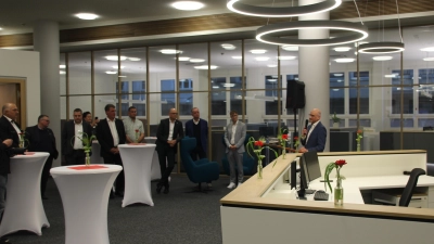 Innenarchitekt Horst Neumeier (rechts, am Mikrofon) erläuterte den Gästen die Idee hinter der Neugestaltung der Sparkassen-Kundenhalle. Im Hintergrund sieht man die verglasten Beratungsräume. (Foto: Robert Maurer)