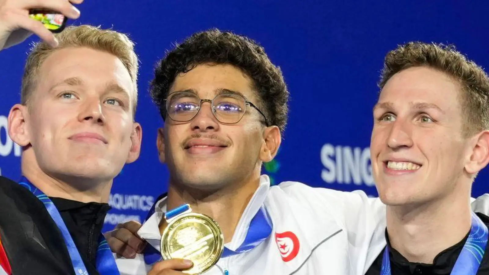 Sven Schwarz hält den für ihn historischen Moment mit dem Handy fest. (Foto: Vincent Thian/AP/dpa)