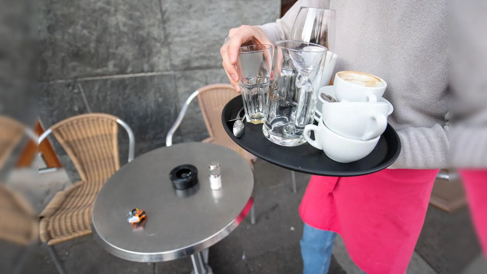 Eine Servicekraft räumt die Tische in einem Café ab. (Foto: Sebastian Gollnow/dpa/Symbolbild)