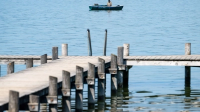 Ein Mann auf seinem Ruderboot angelt auf dem Ammersee in der Bucht von Herrsching. Mitte der Woche könnten es in manchen Orten Bayerns an die 30 Grad warm werden. (Foto: Peter Kneffel/dpa)