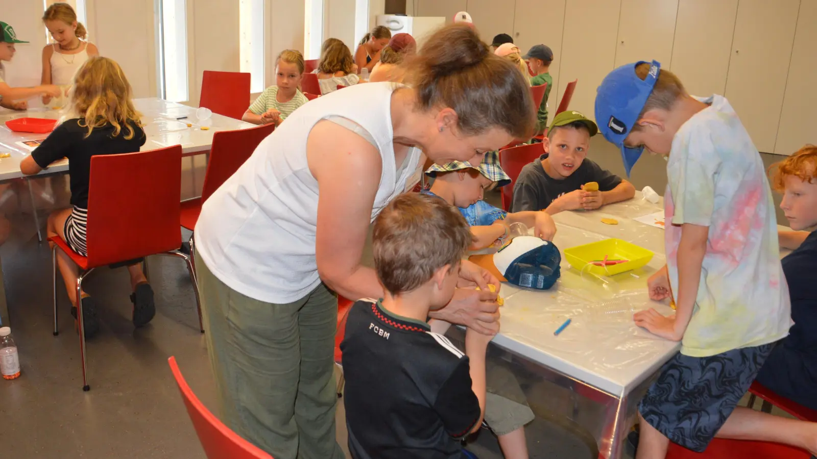 Kinder aus den Gemeinden rund um den Römerpark bastelten ihre eigenen Glücksbringer im Mehrzweckraum des Limeseums. Maike Schneider erklärt den Mädchen und Jungen nicht nur, wie das geht, sondern auch die Bedeutung, die im antiken Rom dahinter steckte. (Foto: Peter Tippl)
