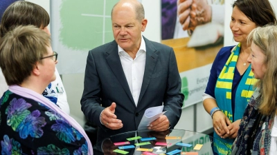 Kanzler Olaf Scholz unterhält sich bei einem Rundgang auf dem Messegelände. (Foto: Daniel Karmann/dpa)