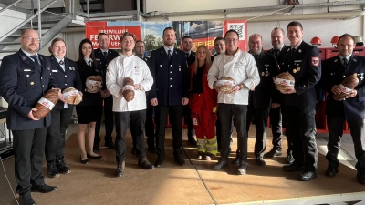 Die Bäcker Michael Merkel (rechts in Weiß) und Maximilian Wimmer (links in Weiß) übergaben in Uehlfeld ihre Spende aus der Aktion Florianskruste an zahlreiche Feuerwehrvertreter aus dem Landkreis.  (Foto: Volker Raab)