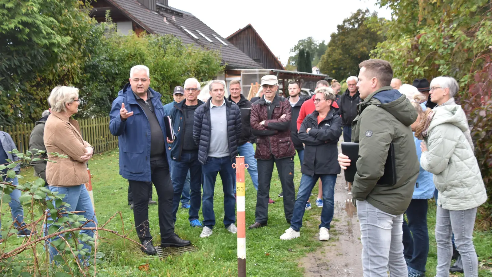 Mit Worten und Händen versuchte Bürgermeister Claus Seifert (Zweiter von links) dem Bauausschussmitgliedern und den zahlreichen Ortstermingästen die Sachlage für den Weg zu erläutern, der seit vielen Jahren mit einem Pfosten für den Schleichverkehr unpassierbar gemacht wurde. (Foto: Andreas Reum)