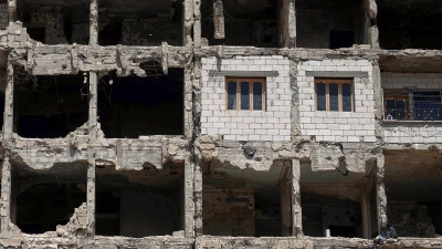 Die Wände und Fenster einer kürzlich restaurierten Wohnung ragen aus einem beschädigten Wohnhaus im vom Krieg zerstörten Viertel Al-Waer heraus. (Foto: Ghaith Alsayed/AP/dpa)