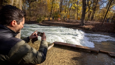 Freizeitsurfer Alexander Neumann fotografiert die - zurzeit nicht funktionstüchtige - Eisbachwelle im Englischen Garten. (Foto: Peter Kneffel/dpa)