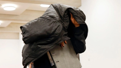 Der ehemalige Security-Mann bedeckt im Gerichtsaal seinen Kopf mit einer Jacke. (Foto: Daniel Löb/dpa)
