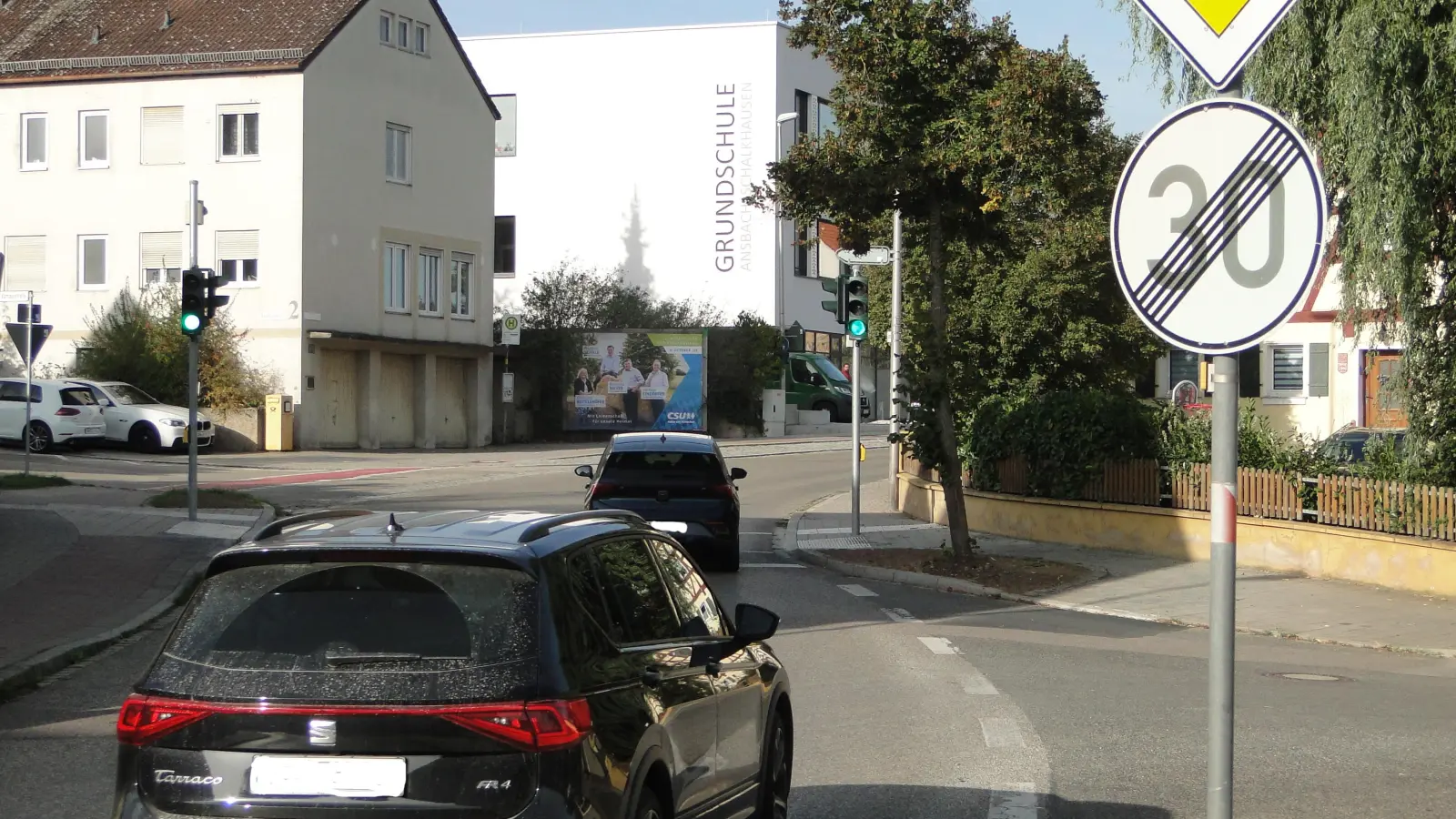 Das Verkehrsschild mit der durchgestrichenen 30 steht unmittelbar vor der Ampel, die die Schulkinder sicher über die Straße bringen soll. Im Hintergrund ist die neue Grundschule zu sehen. (Foto: Winfried Vennemann)