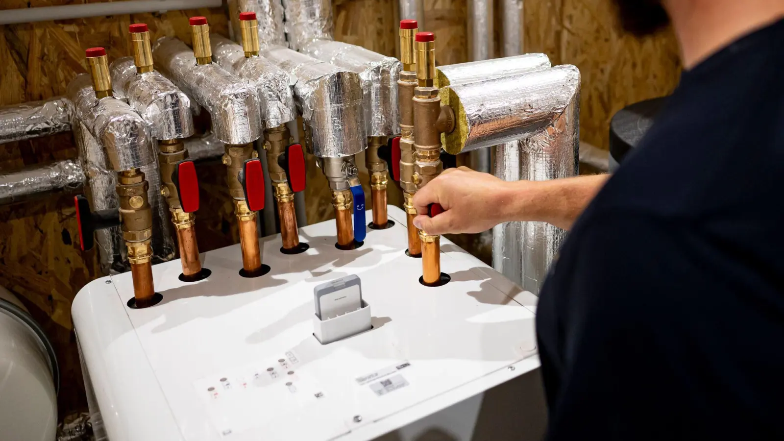 Ein Handwerker arbeitet an einer Wärmepumpe. Bei den Geräten ist die Nachfrage eingebrochen. (Foto: Fabian Sommer/dpa)