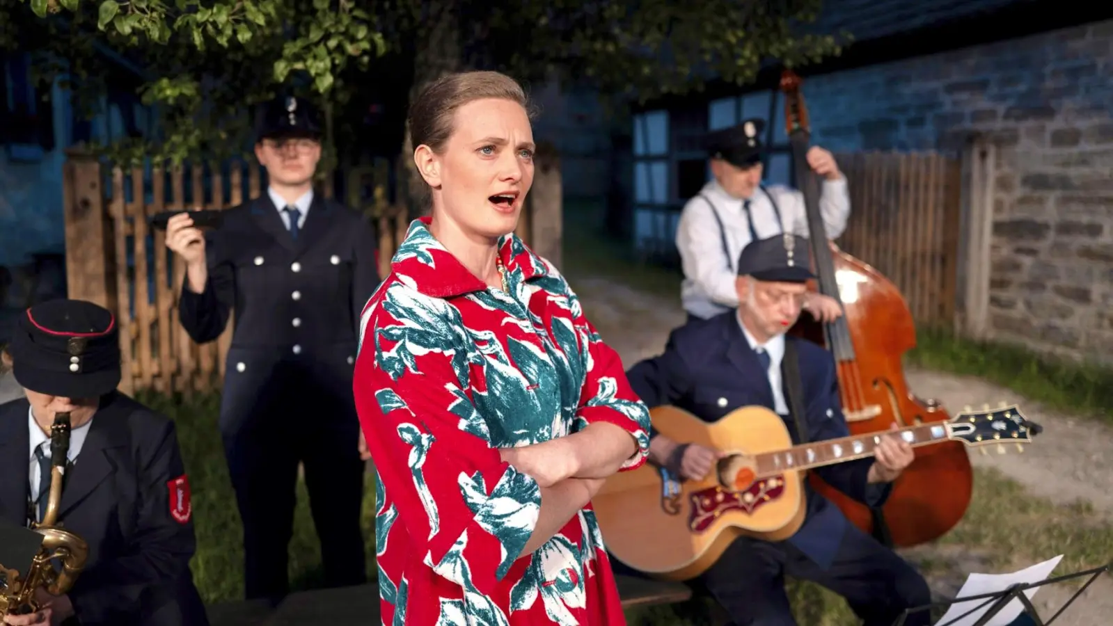 Mitte der 1960er-Jahre spielt „Der Sommergast”, eine Komödie des Freilandtheaters im Fränkischen Freilandmuseum Bad Windsheim. Das Foto zeigt eine Szene mit Luise Hagediese Bernburg und der Feuerwehrkapelle des Stücks. (Foto: Andreas Riedel)