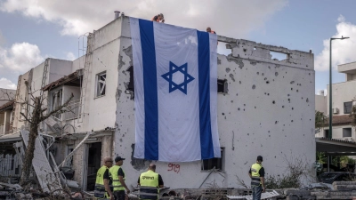 Eine riesige israelische Fahne hängt vom Dach eines beschädigten Gebäudes in Kiriat Bialik. (Foto: Ilia Yefimovich/dpa)