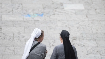 Zwei Besucherinnen des Katholikentags sitzen auf einer Treppe. (Foto: Marijan Murat/dpa)