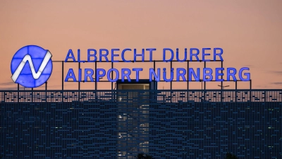 Der Schriftzug „Albrecht Dürer Airport Nürnberg“ leuchtet auf dem Dach eines Parkhauses am Flughafen am Abend. (Foto: Daniel Karmann/dpa)