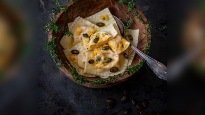 Einen Teil der Kürbis-Ricotta-Mischung wird zum Servieren über die Ravioli verteilt und mit gerösteten Kürbiskernen und Parmesan getoppt. (Foto: Valerie Hammacher/ars vivendi/dpa-tmn)