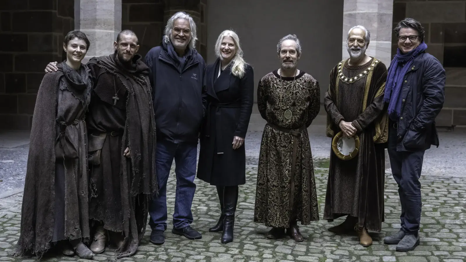Die Dreharbeiten zu „The Uprising” sind beendet. Auf dem Foto am Set im historischen Innenhof vom Pellerhaus in Nürnberg: Von links nach rechts: Thomasin McKenzie (Schauspielerin) und Jamie Bell (Schauspieler), Paul Greengrass (Regisseur, Drehbuchautor, Produzent), Judith Erber (Co-Leiterin Förderabteilung FFF Bayern), Tom Hollander (Schauspieler), Mark Redhead (Schauspieler) sowie Philipp Kreuzer (Produzent, Supernix). (Foto: Betina la Plante/FilmFernsehFonds GmbH)