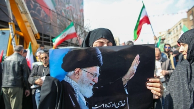 Eine Trauernde hält beim Begräbnis des von Israel getöteten Generalsekretärs des iranischen Sicherheitsrats, Ali Laridschani, ein Bild des ebenfalls getöteten Obersten Führers Ajatollah Ali Chamenei in die Höhe.  (Foto: Stringer/dpa)