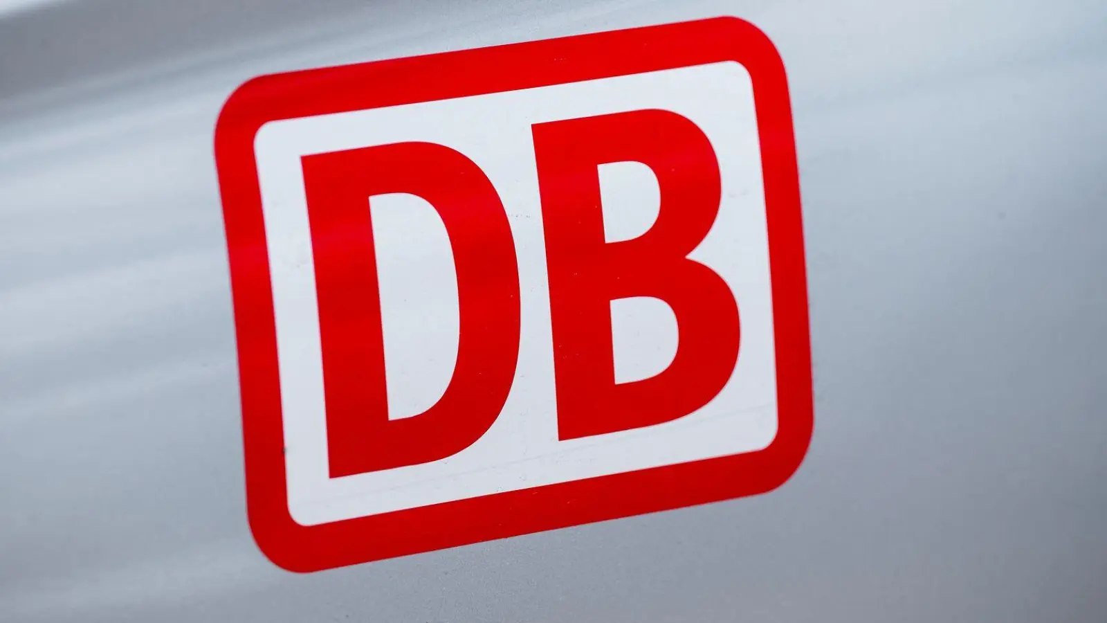 Das Logo der Deutschen Bahn auf einem Auto. Die DB will jahrelang das Bahnangebot in Oberstdorf wegen Bauarbeiten einschränken. Fernverkehrszüge sollen dann gar nicht mehr in die Urlaubsregion in den Allgäuer Alpen fahren. (Archivbild-Illustration) (Foto: Daniel Vogl/dpa)