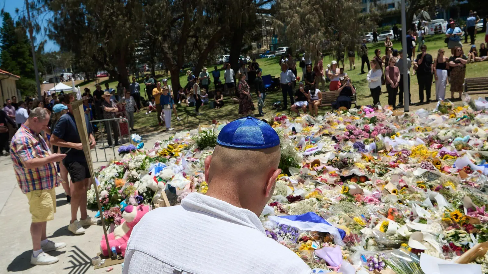 Menschen legen bei einer Gedenkfeier für die Opfer eines Terrorangriffs am Bondi Beach in Sydney Blumen nieder. (Foto aktuell) (Foto: Flavio Brancaleone/AAP/dpa)