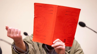 Der Angeklagte verdeckte sein Gesicht zum Prozessauftakt zunächst mit einer Mappe. (Foto: Peter Kneffel/dpa)