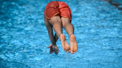 Lockte der Sprung ins kühle Nass? Ein junger Mann steigt ins noch geschlossene Freibad ein. (Symboldbild)    (Foto: Bernd von Jutrczenka/dpa)